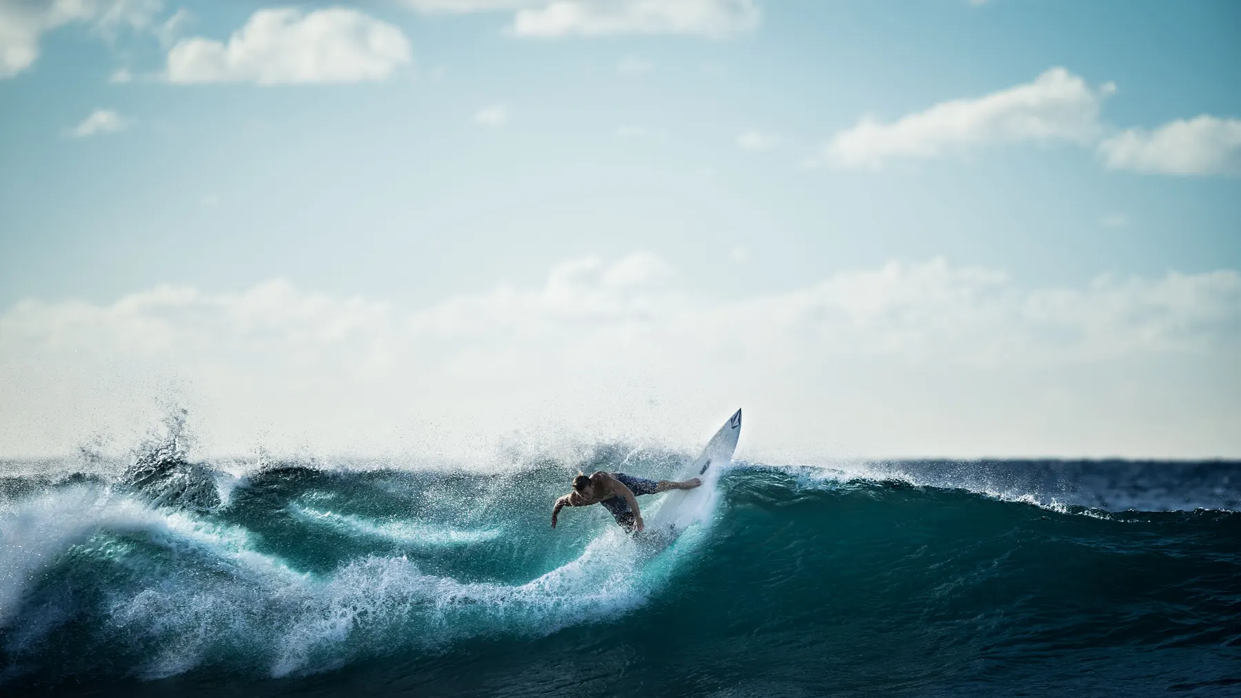A surfer carving down the face of a wave